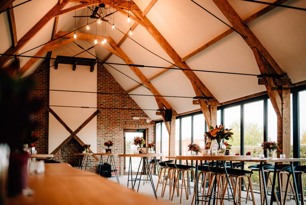 Sfeervolle landelijke zaal met houten balken en daglicht tijdens een trouwfeest met overnachting
