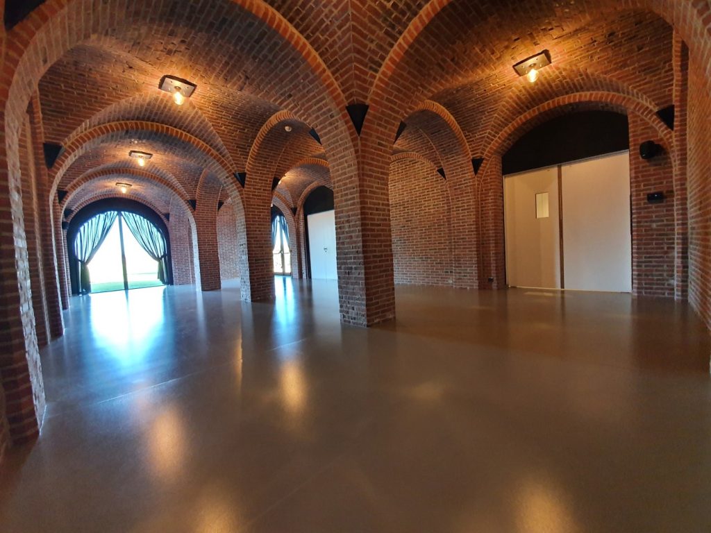Open ruimte van het Cellarium bij ’t Convent met gemetste pilaren, boogvormig plafond en zicht op de tuin