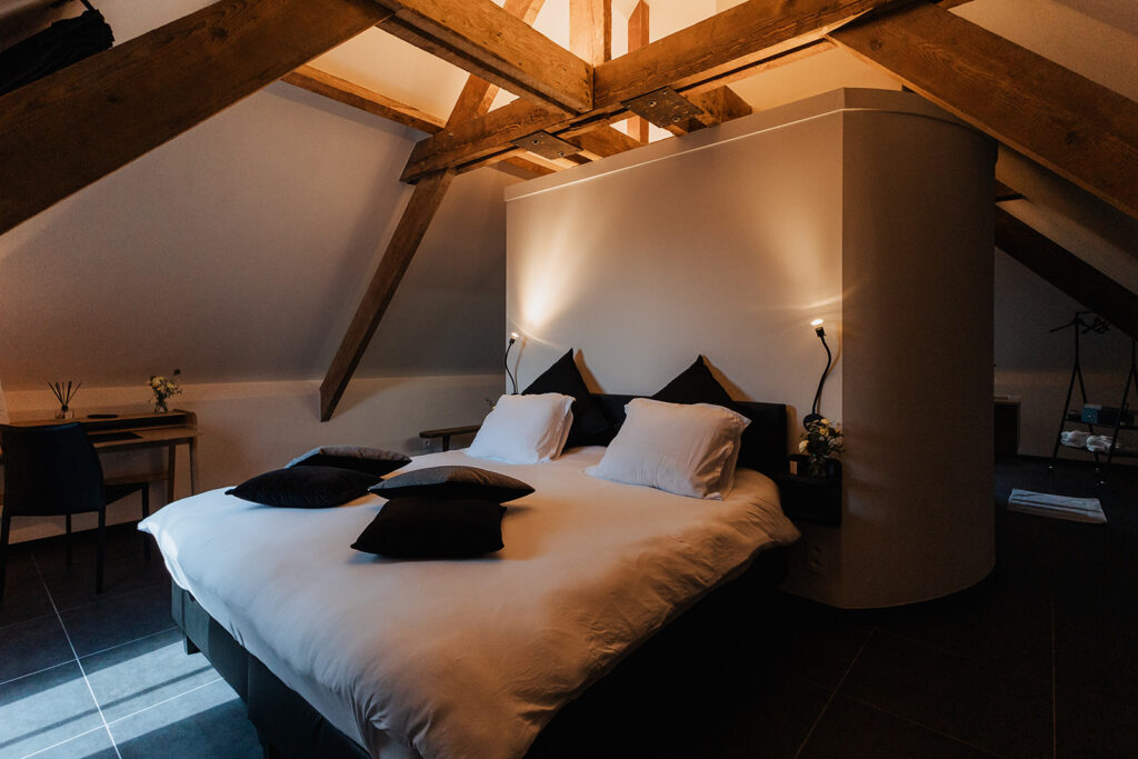 Sfeervolle kamer met houten balken en comfortabel bed voor trouwfeest met overnachting.
